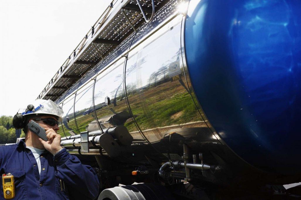 Truck driver on a phone next to a tanker